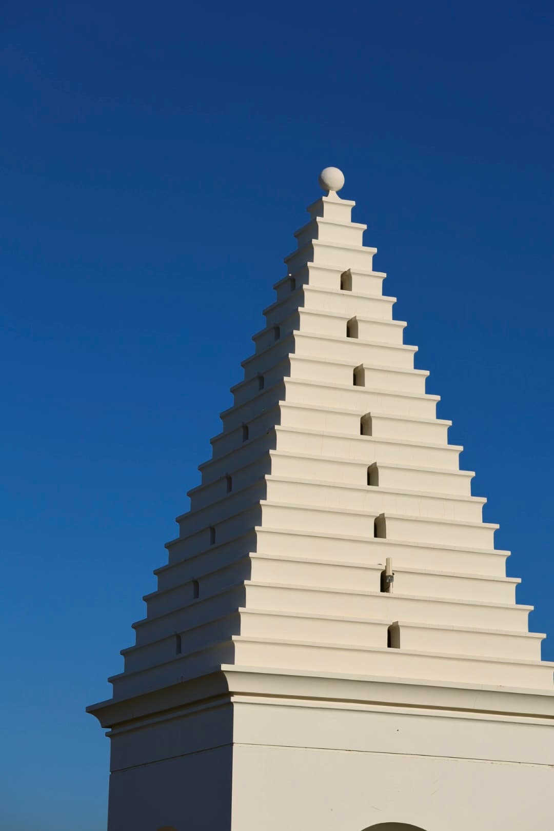 Whitewashed stepped-gable spire against a deep blue sky, 30A